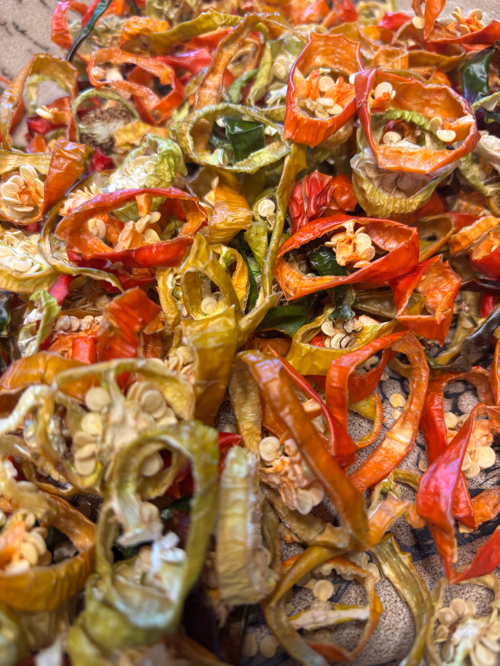 Dried sliced peppers in various colors on a textured surface